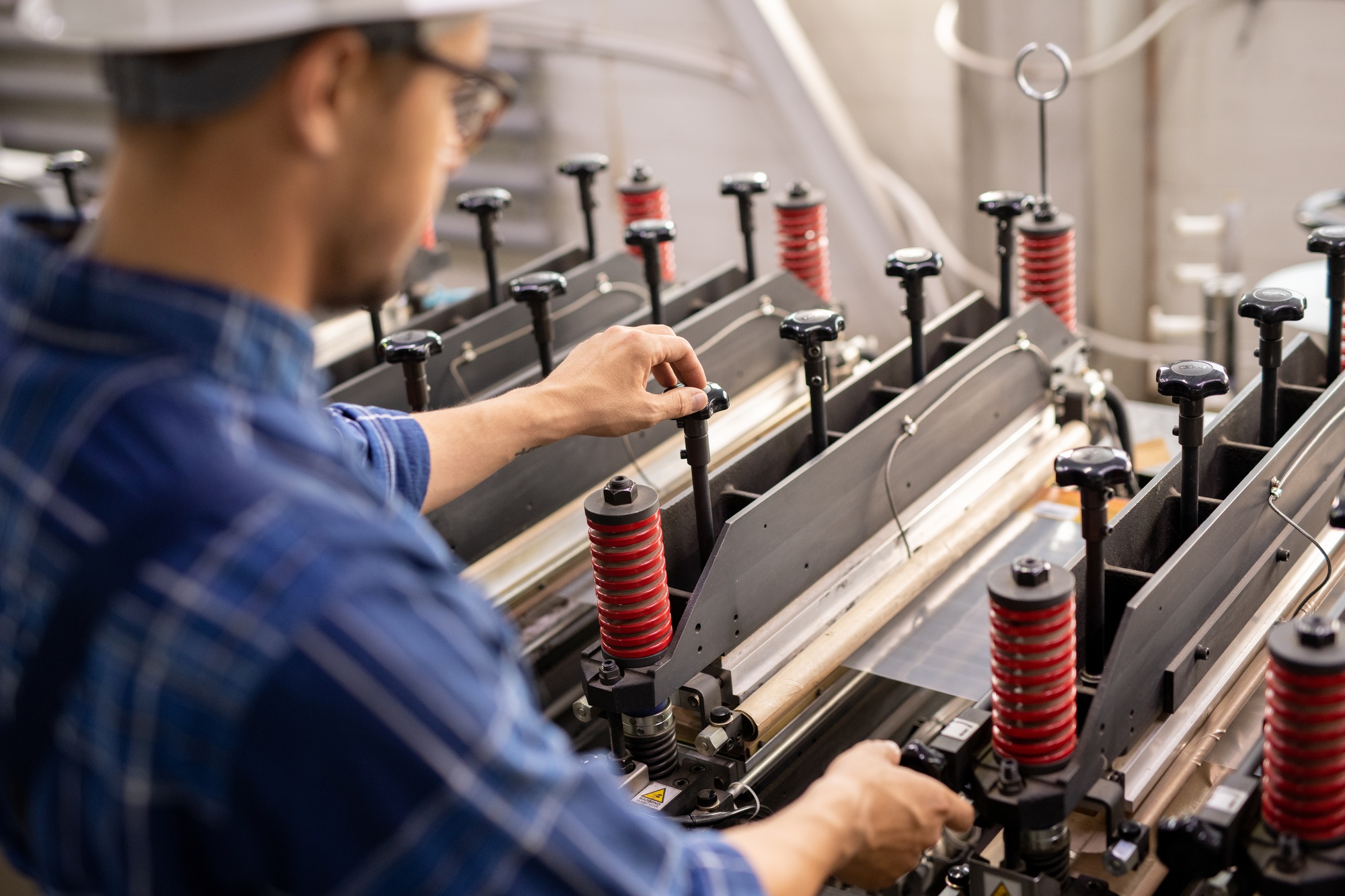 Industrial equipment being operated by young professional technician or engineer